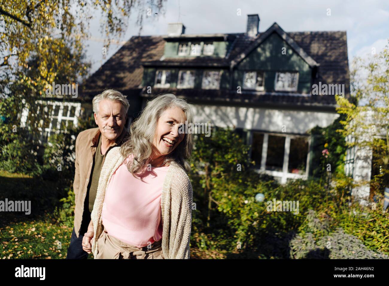 Gerne älteres Paar im Garten ihres Hauses im Herbst Stockfoto