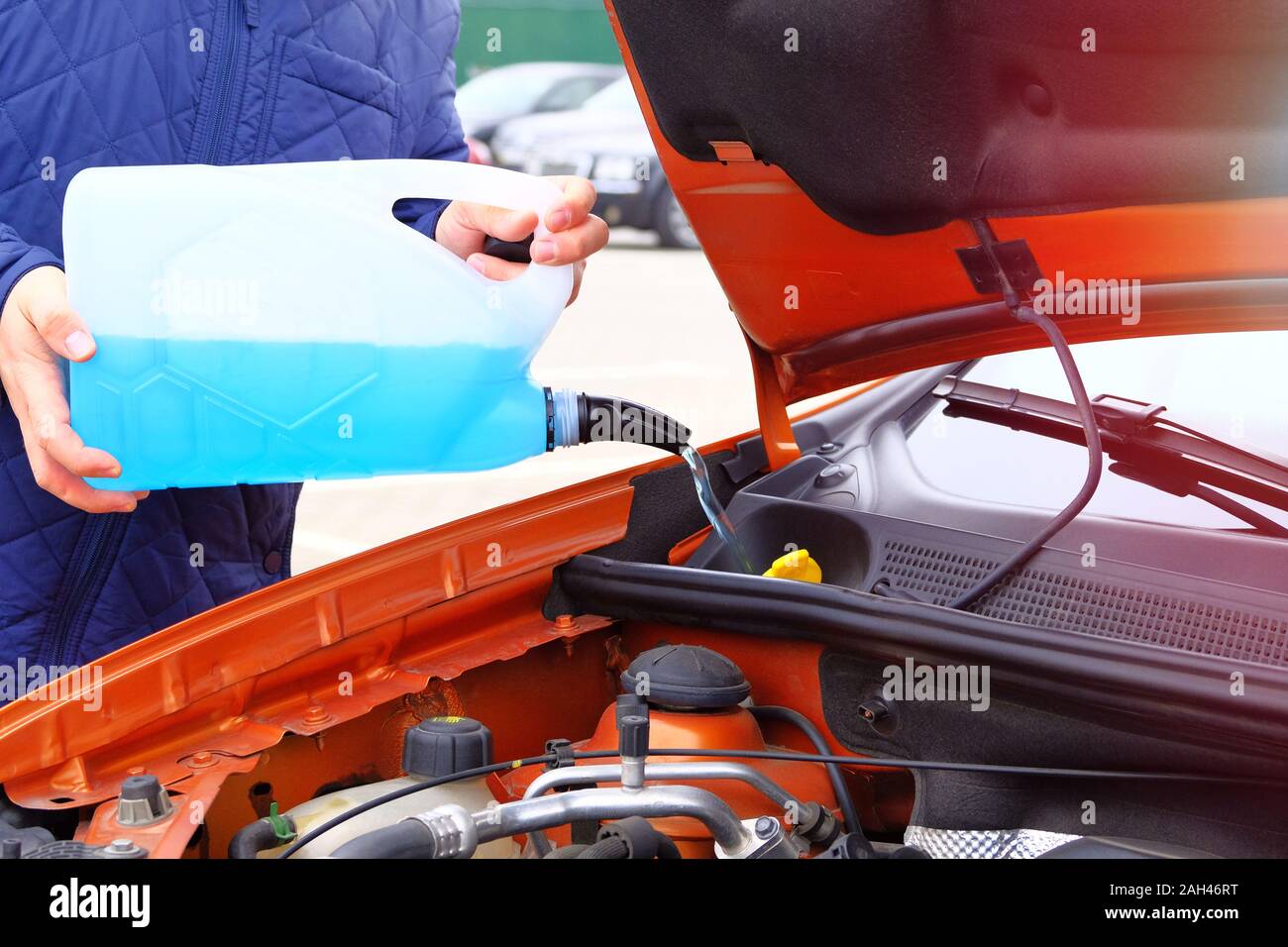Treiber mit blauer Flüssigkeit der Scheibenwaschanlage in seinen Händen, bis zu schließen. Auto Wartung Konzept. Befüllung Scheibenwaschanlage Waschflüssigkeit auf Orange. Stockfoto Treiber mit blauer Flüssigkeit der Scheibenwaschanlage in seinen Händen, bis zu schließen. Auto Wartung Konzept. Befüllung Scheibenwaschanlage Waschflüssigkeit auf Orange. Stockfoto