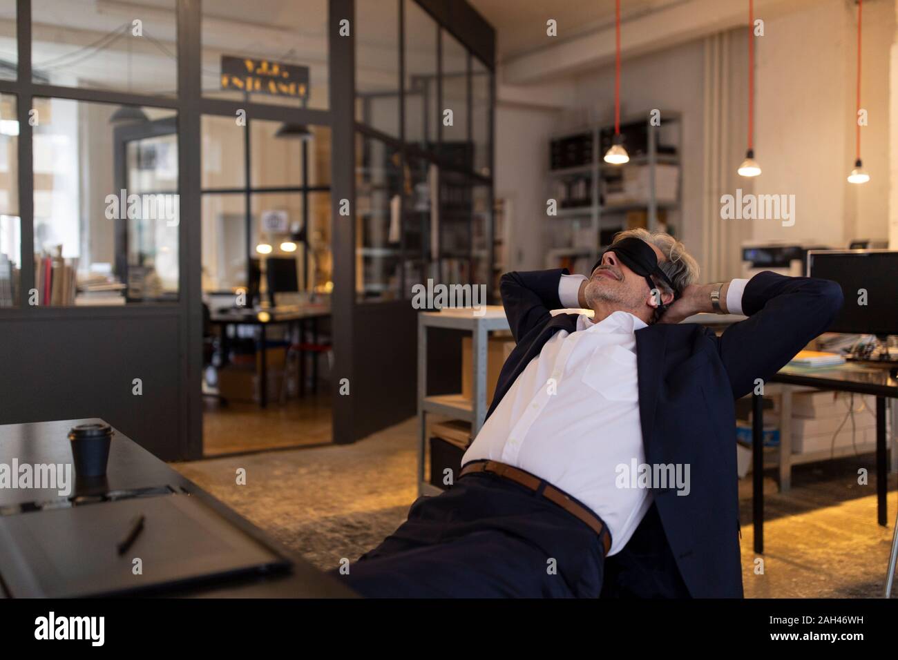 Senior Geschäftsmann mit einem Power Nap am Schreibtisch im Büro Stockfoto