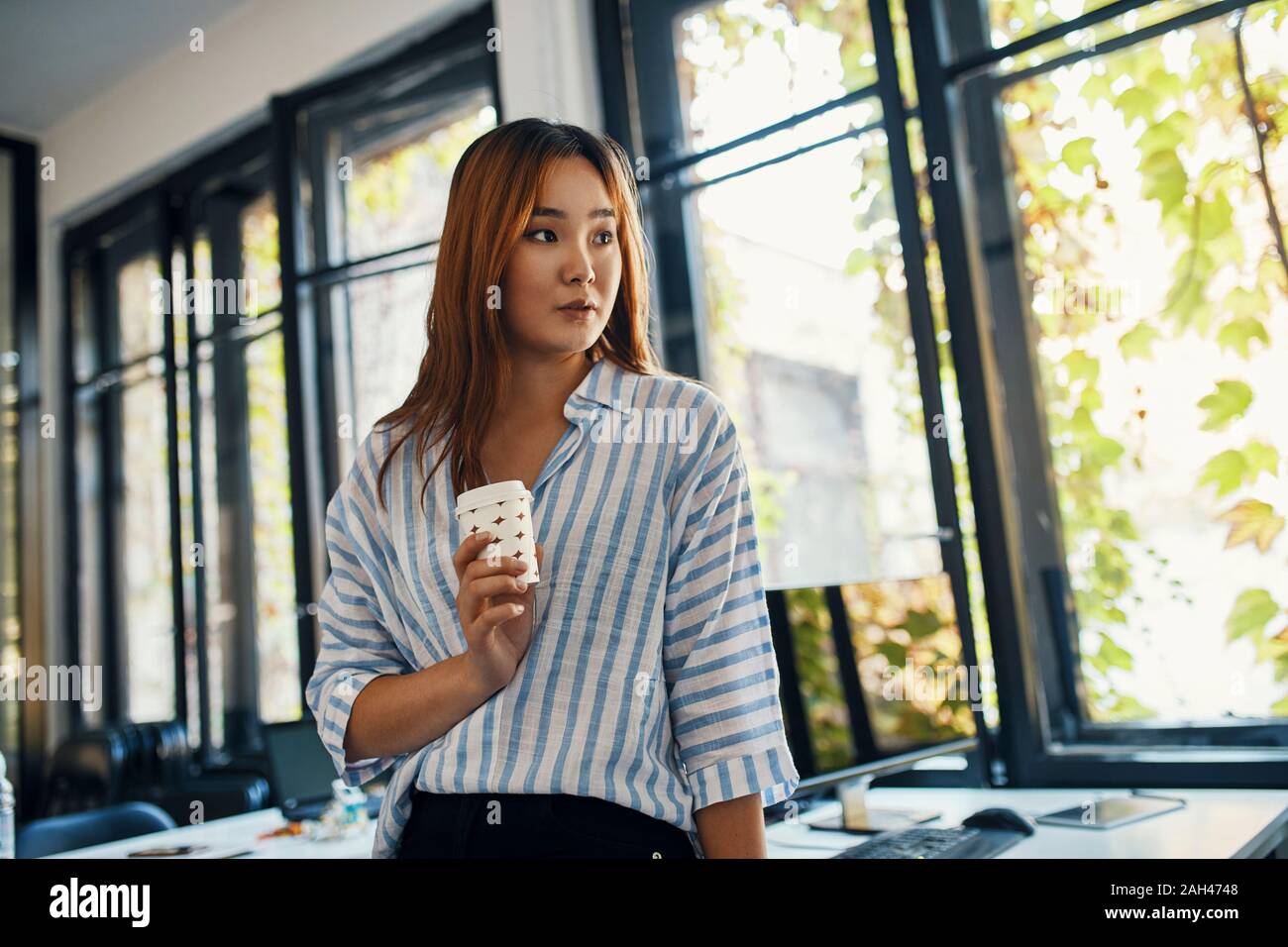 Geschäftsfrau mit einer Kaffeepause im Büro Stockfoto