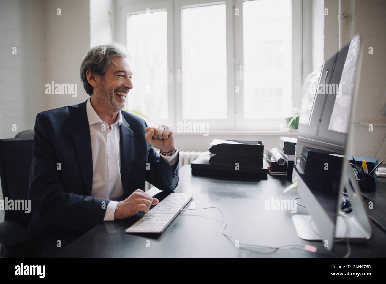 Lachend älterer Geschäftsmann am Schreibtisch im Büro arbeiten Stockfoto