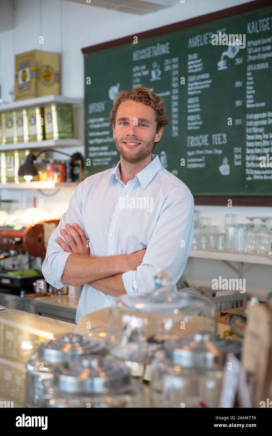 Junge Unternehmer in einem Cafe, mit verschränkten Armen hinter dem Zähler Stockfoto