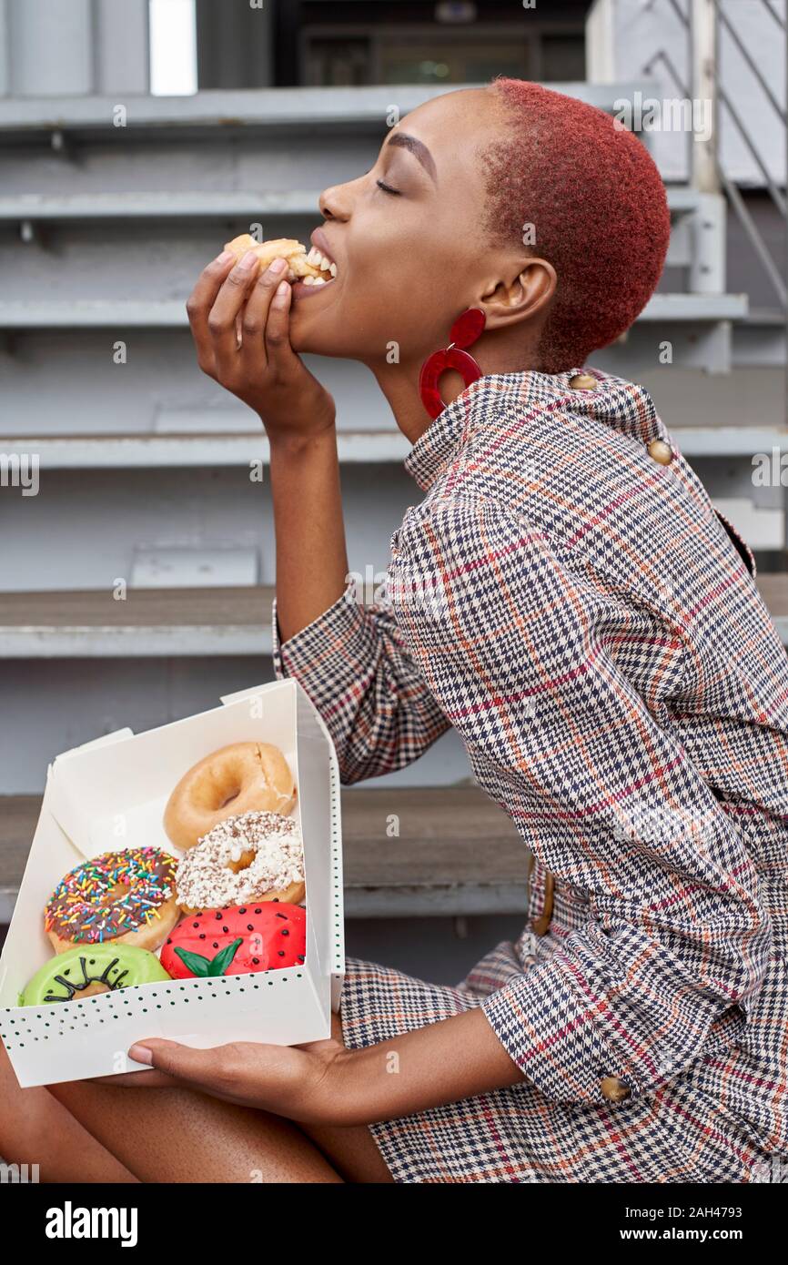 Junge Frau essen einen Donut aus der Box Stockfoto