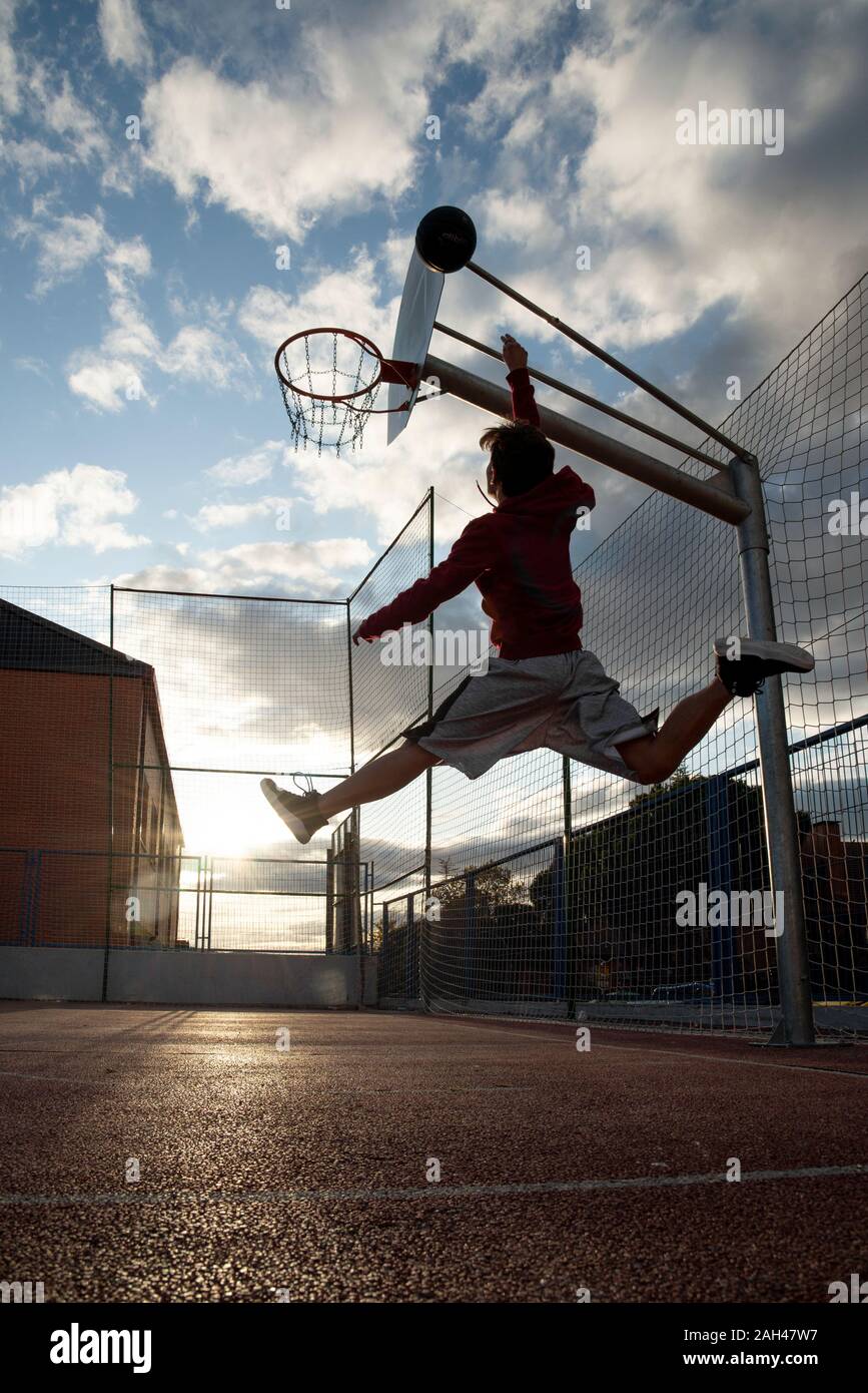 Teenager spielen Basketball, dunking gegen die Sonne Stockfoto