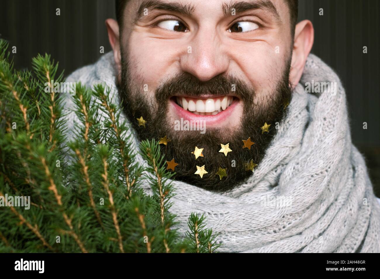 Lustiger Mann mit Weihnachtsbaum und Goldene Sterne in seinen Bart Stockfoto