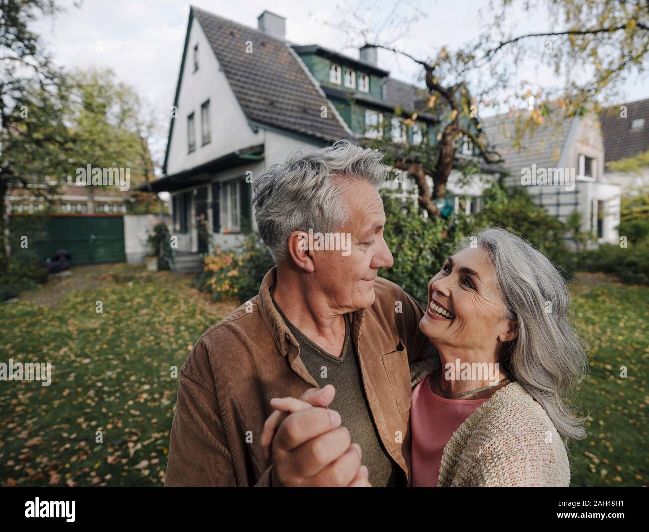 Gerne älteres Paar im Garten ihres Hauses im Herbst Stockfoto