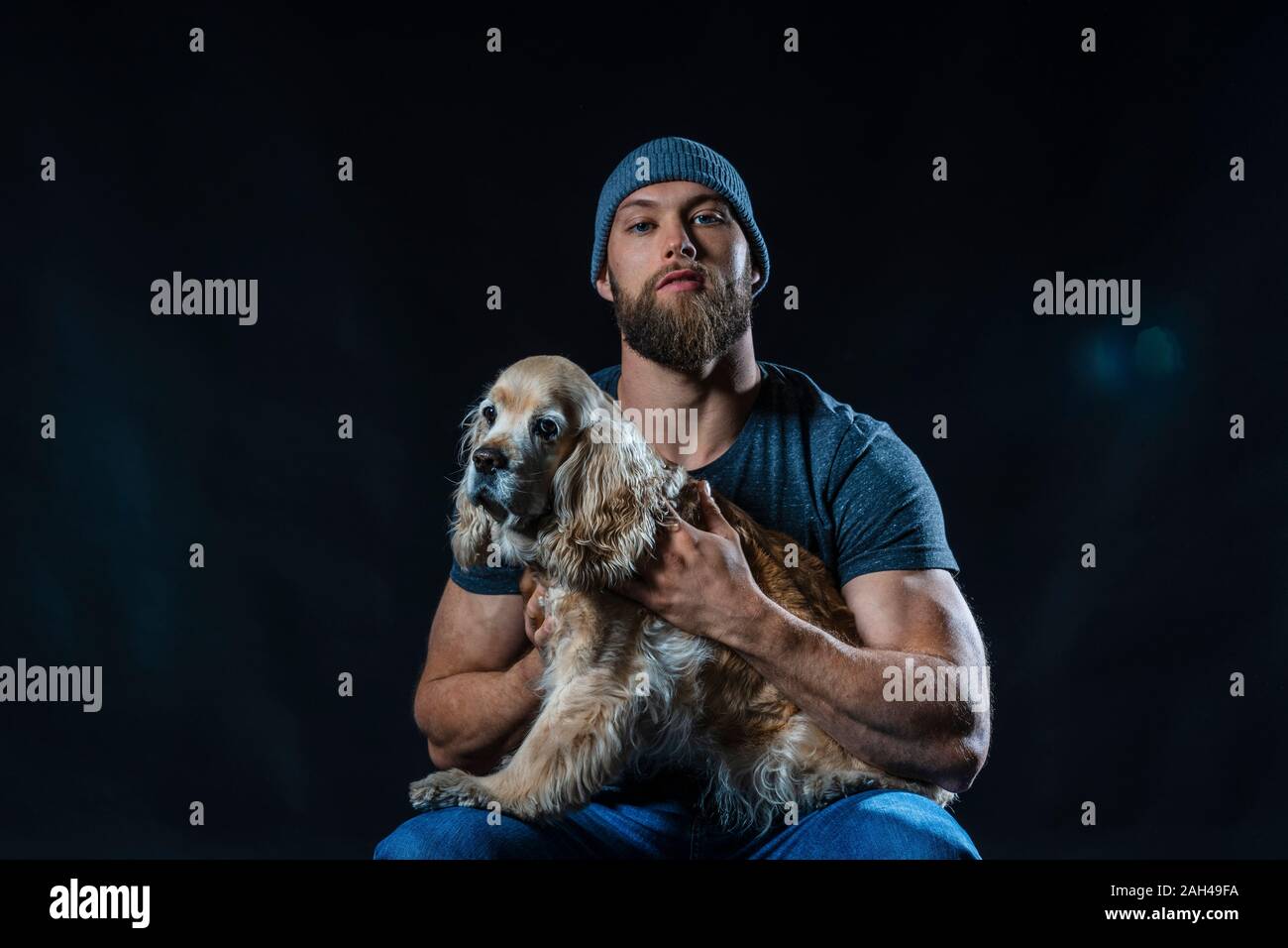 Porträt eines muskulösen Mann sitzt im Studio mit einem Hund Stockfoto