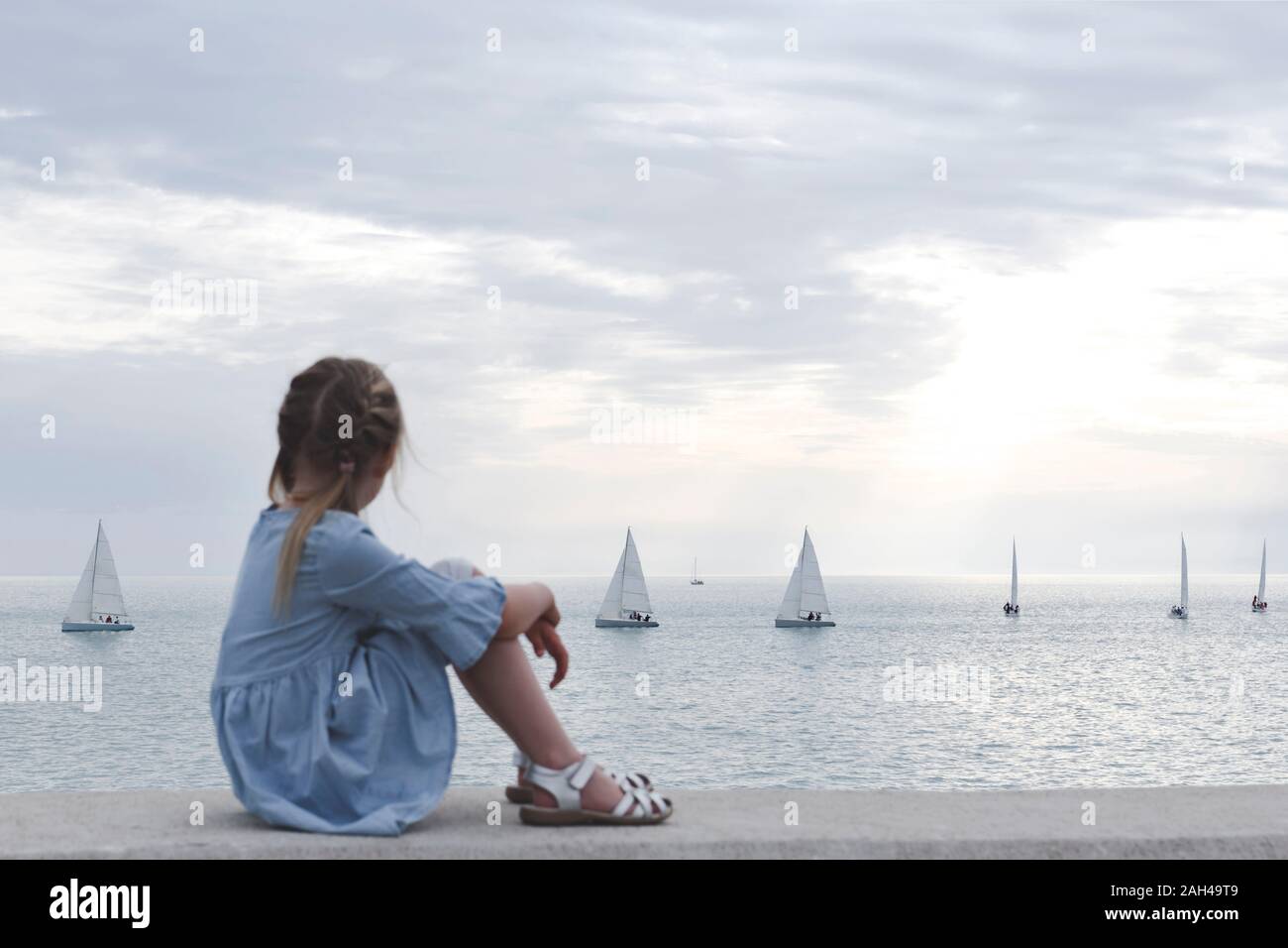Bisschen Mädchen mit Blick auf das Meer und die Boote Stockfoto