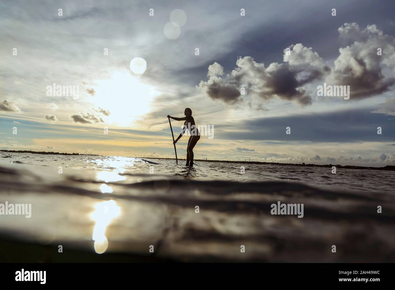 Weibliche SUP Surfer bei Sonnenuntergang, Bali, Indonesien Stockfoto