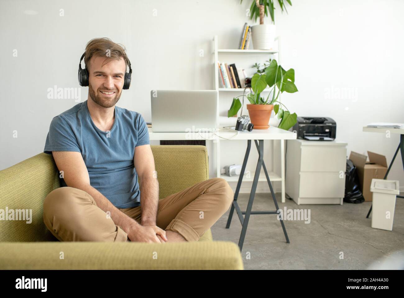 Portrait von lächelnden Mann sitzt auf der Couch im Büro Musik hören Stockfoto