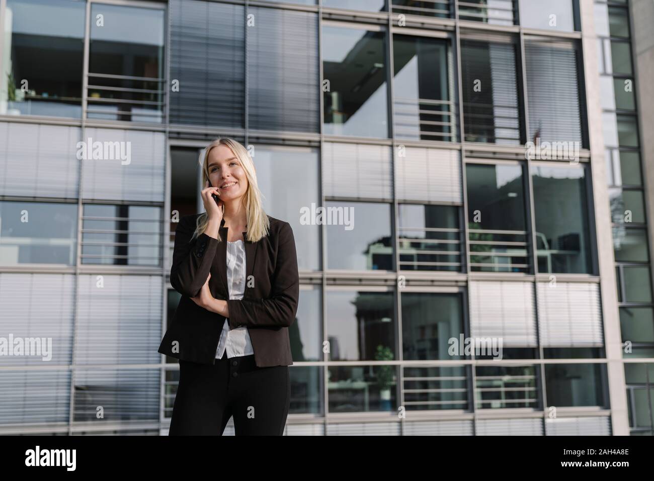 Blond Geschäftsfrau mit Smartphone im Hintergrund modernes Gebäude Stockfoto