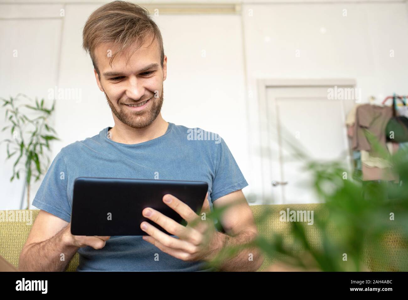 Lächelnd Mann sitzt auf mit Tablet couch Stockfoto