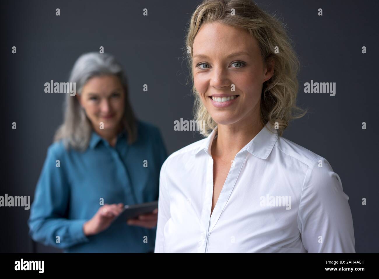 Portrait von lächelnden jungen Geschäftsfrau mit Reife Geschäftsfrau im Hintergrund Stockfoto