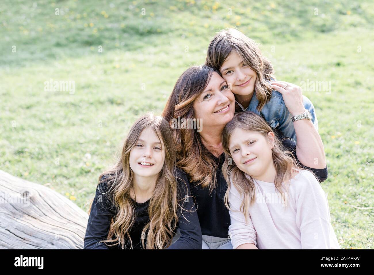 Portrait von lächelnden Mutter mit drei Triplet Töchter auf einer Wiese Stockfoto