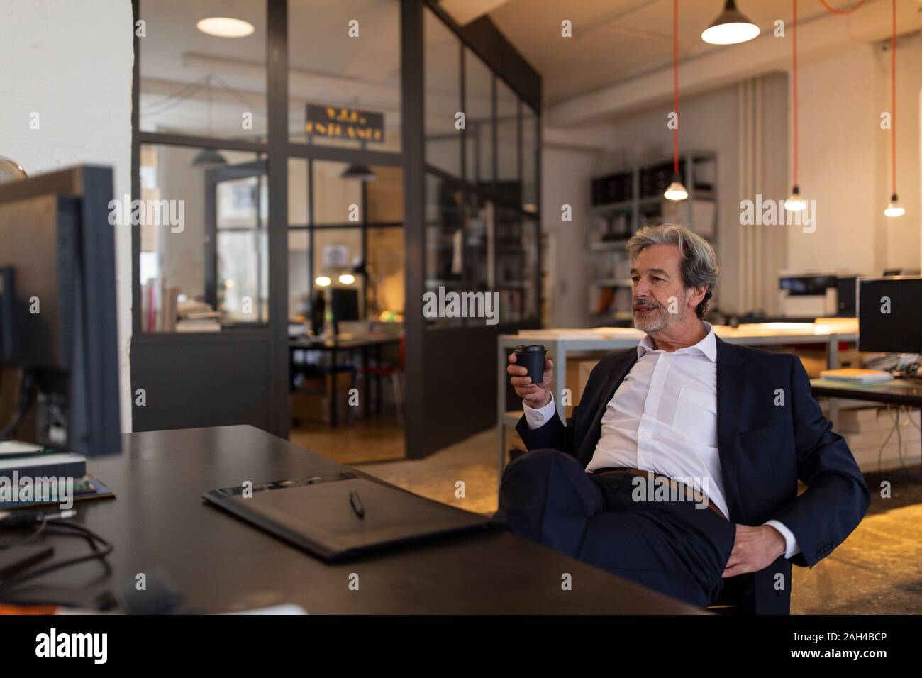 Entspannt älterer Geschäftsmann am Schreibtisch im Büro sitzen Stockfoto