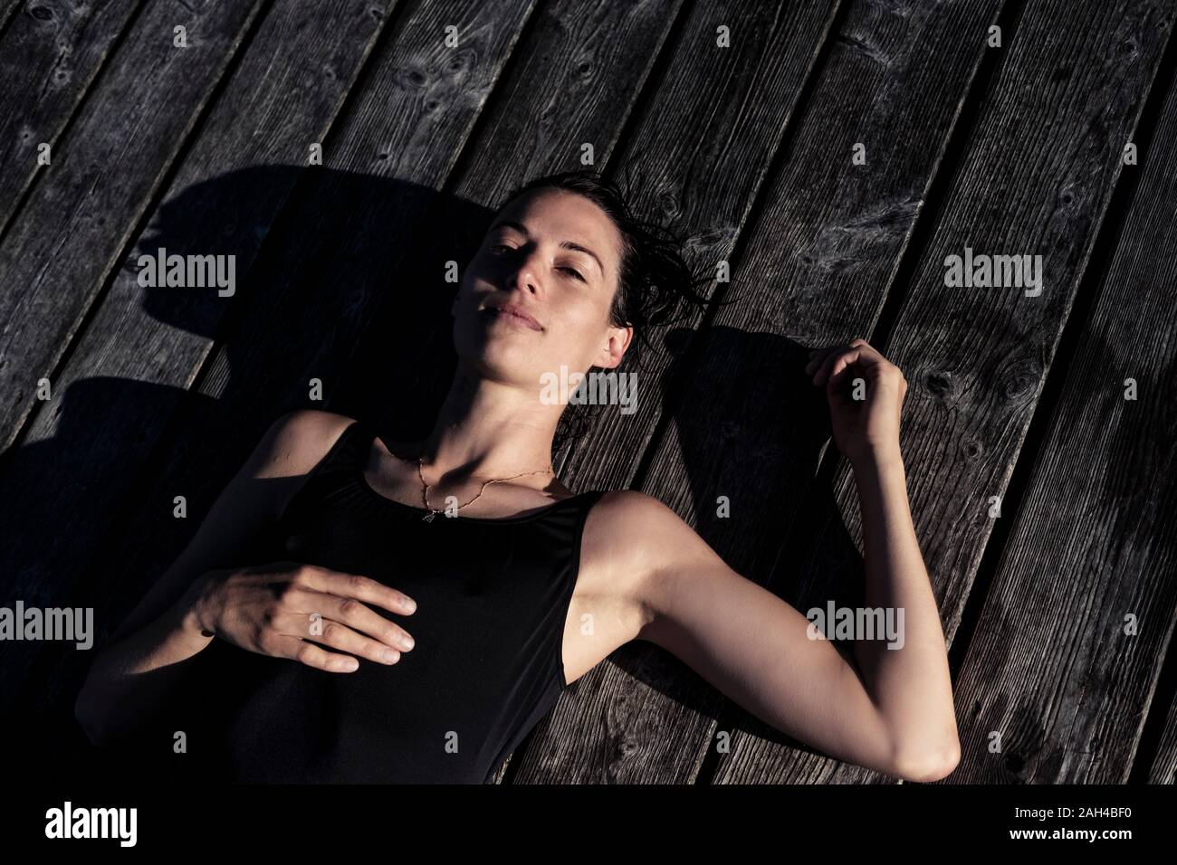 Portrait von einer Frau mit schwarzen Badeanzug liegen auf einem Steg Stockfoto