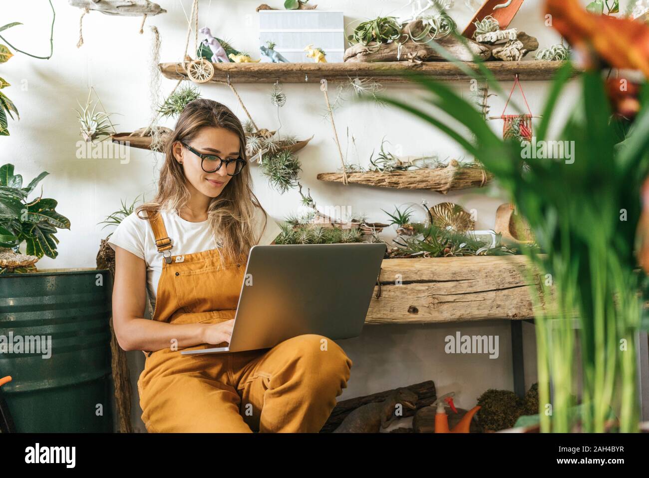 Junge Frau mit Laptop in einem kleinen Garten shop Stockfoto
