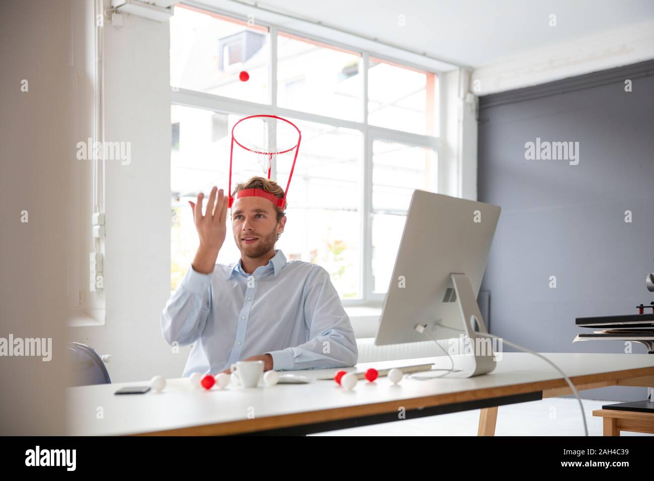 Junge Unternehmer in seinem Büro, das Werfen einer Kugel in einem Hoop Stockfoto