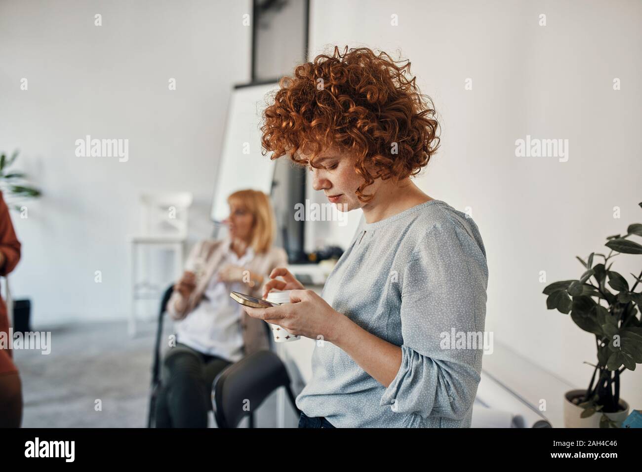 Geschäftsfrau eine Pause im Büro mit Smartphone Stockfoto