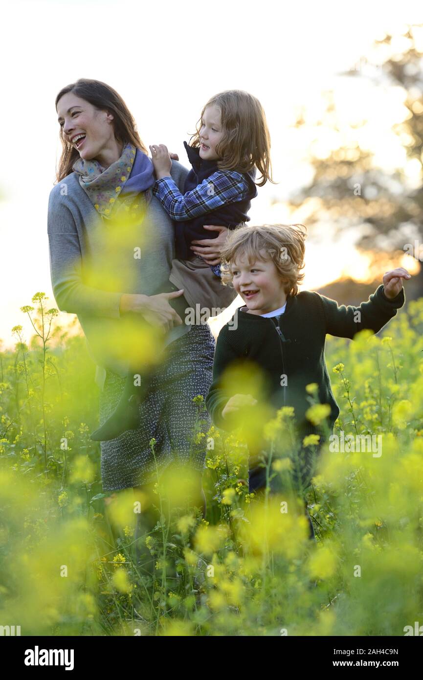 Die Mutter ihre Tochter tragen, Wandern mit Sohn über Blumenwiese Stockfoto