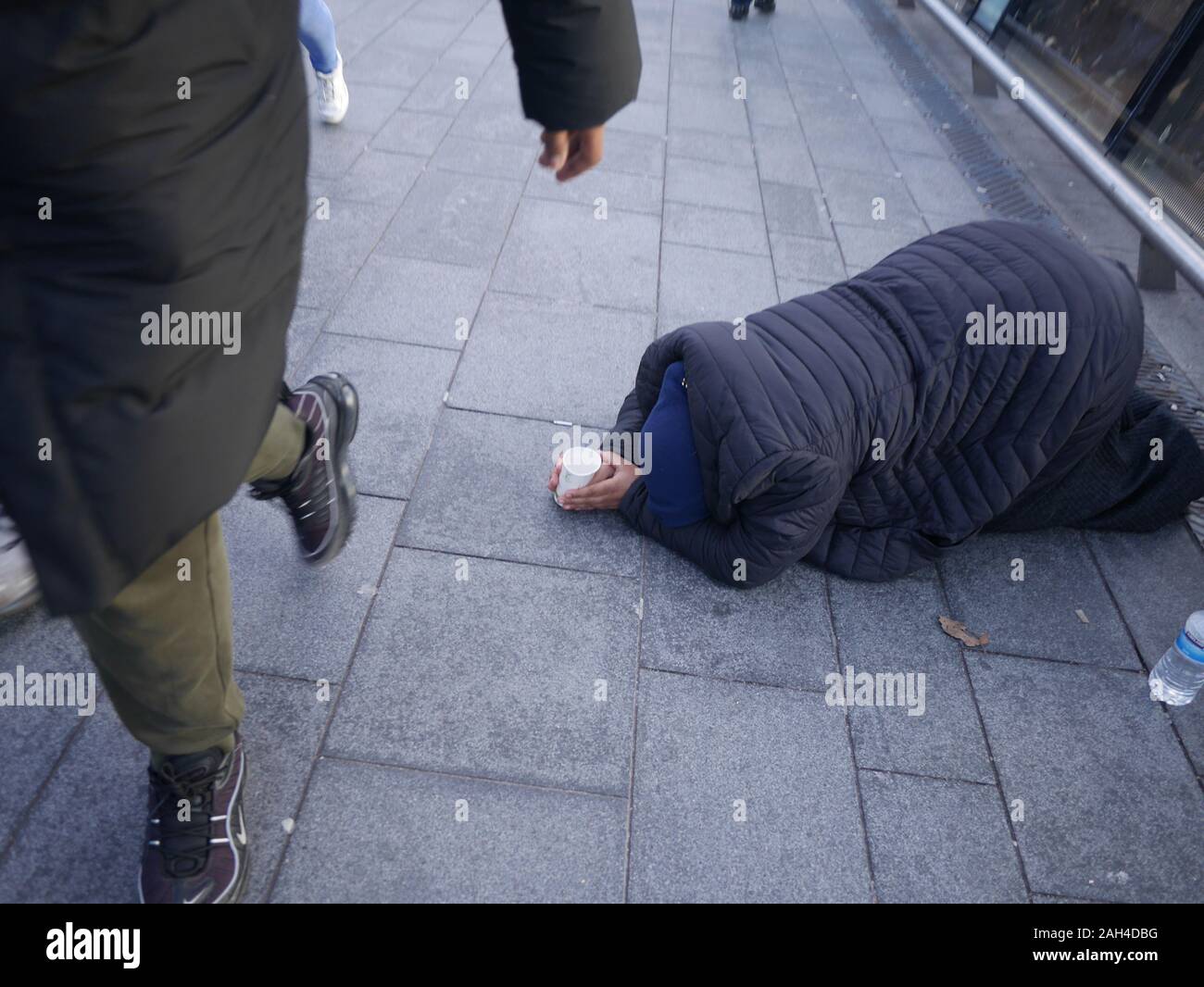 Reiche Arme teilen Ungleichheit, obdachloser Prostata-Bettler mit Tasse bettelt um Geld London, kniet sich mit Bettelbecher nieder, während die Menschen vorbeigehen Stockfoto Reiche Arme teilen Ungleichheit, obdachloser Prostata-Bettler mit Tasse bettelt um Geld London, kniet sich mit Bettelbecher nieder, während die Menschen vorbeigehen Stockfoto