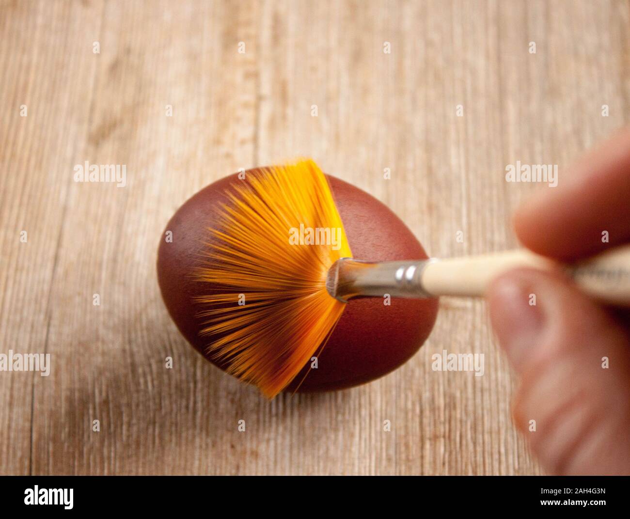 Menschliche Hand Malerei Osterei mit der Bürste. Top natürliche woodan Hintergrund anzeigen. Selektive Weichzeichner. Geringe Tiefenschärfe. Text kopieren. Ostern c Stockfoto