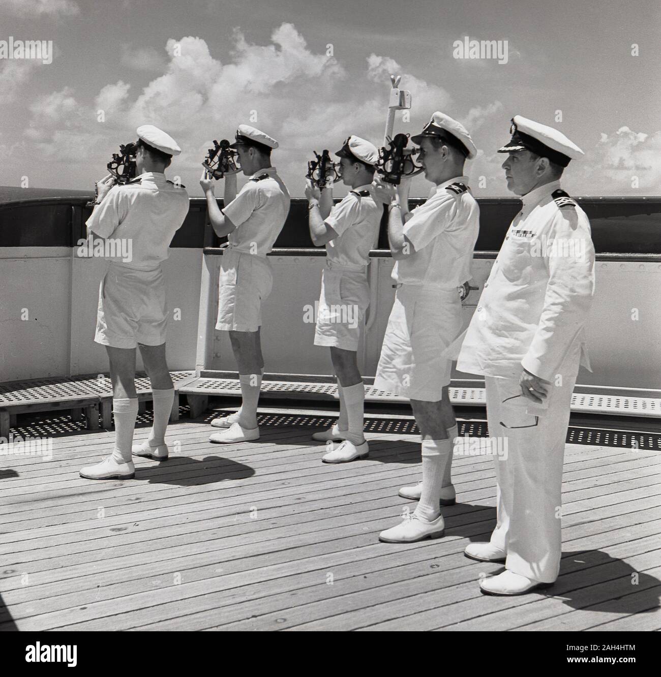 1950, historische, eine Gruppe von vier uniformierte Schiff Navigatoren auf dem Deck eines Dampfschiffes mit Sextanten, betreut durch den Kapitän. Sextanten sind maritime Messgeräte können Sie den Winkel zwischen dem Horizont und einem Himmelskörper wie Sonne, Mond oder Sterne zu bestimmen. Stockfoto