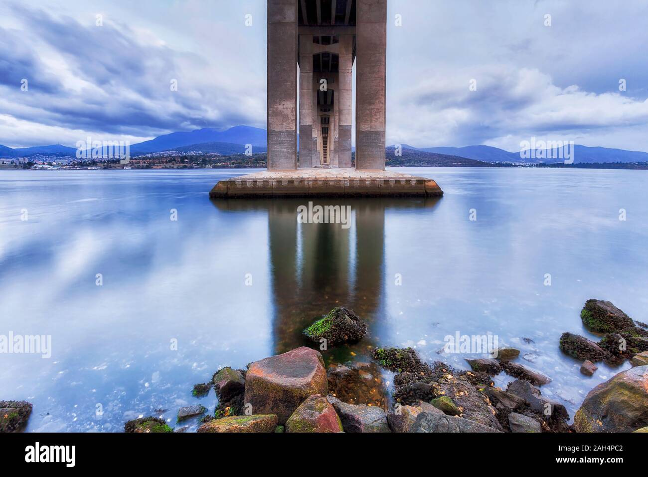 Unterhalb der Tasman Brücke über den Derwent River in Hobart bei Sonnenaufgang, wenn Wolken und Licht im Wasser spiegeln. Stockfoto