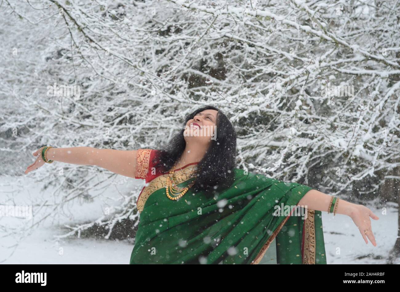 Traditionell gekleidete zuversichtlich indische Frau genießen Schneefall Stockfoto