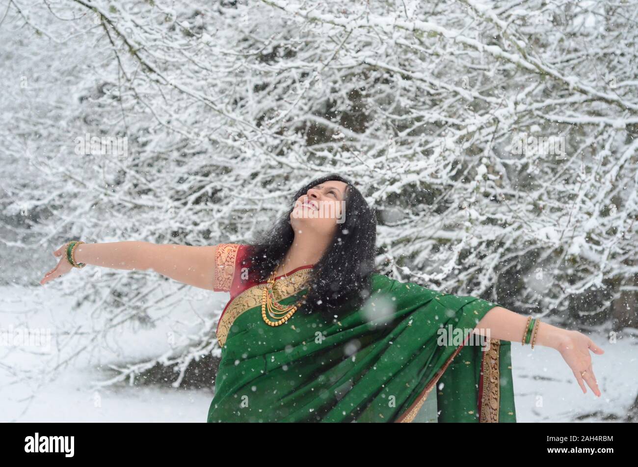 Traditionell gekleidete zuversichtlich indische Frau genießen Schneefall Stockfoto