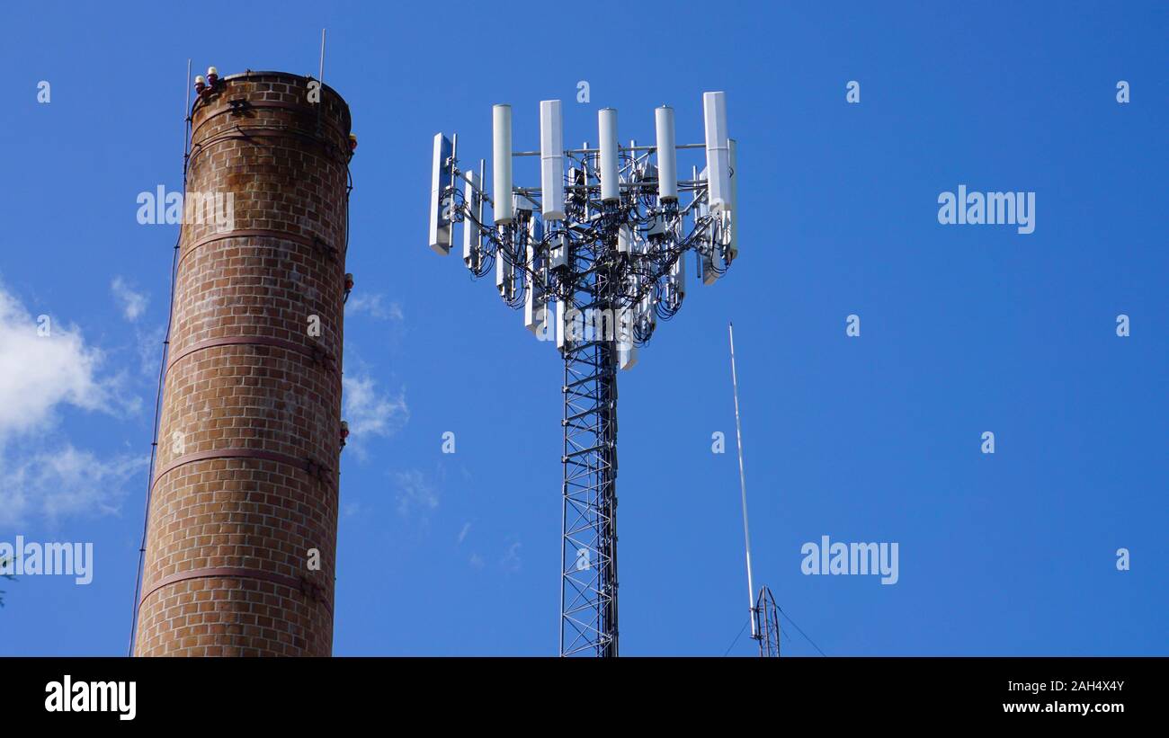 Ziegelstein Schornstein und Radio oder zellulären Turm vor einem blauen Himmel. Fergus Falls, Minnesota. Stockfoto