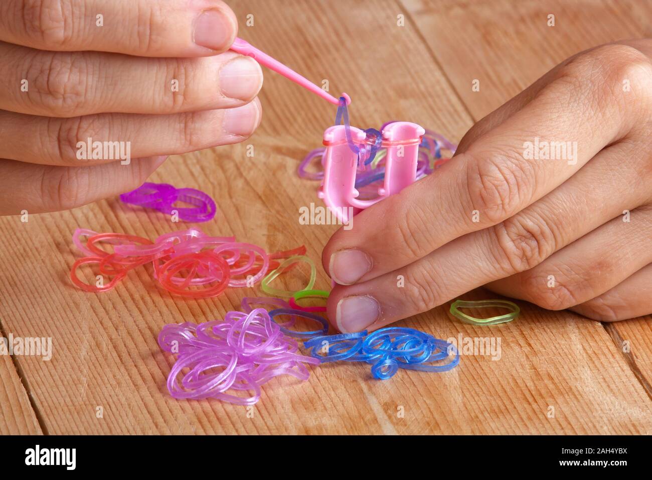 Hände, rubber band Bracelet mit Häkeln und Y-Weber Stockfoto