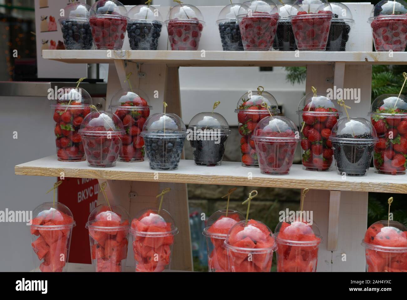 Frische Erdbeeren, Himbeeren, Brombeeren, Heidelbeeren, Wassermelone, in transparenten Teil cups auf einem hölzernen Zähler. Stockfoto