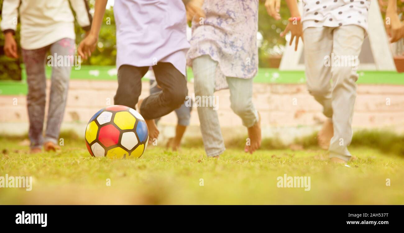 Selektiver Fokus auf Fußball, Gruppe von Kids Running und Fußball spielen im Park-Konzept von spielenden Kindern Spiele im Freien während der Ferien. Stockfoto