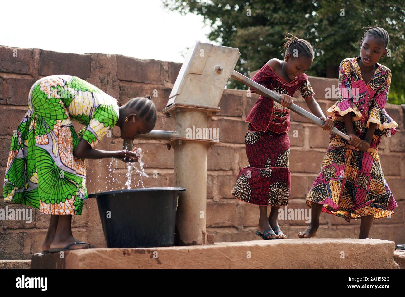 Afrikanische Kinder In EINEM öffentlichen Bohrloch, Die Wasser Für Ihre Familien Holen Stockfoto