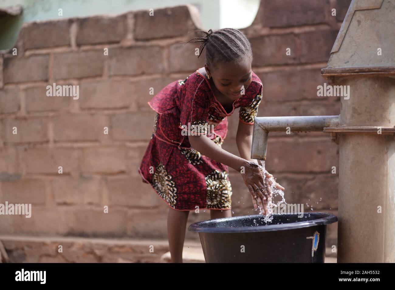 Kleines Afrikanisches Mädchen, Das Ihre Hände Im Dorf Gut Waschen Stockfoto