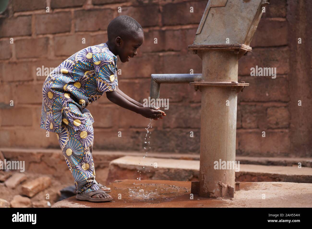 Glücklicher Kleiner afrikanischer Junge, der seine Hände An der Dorfpumpe wasch Stockfoto