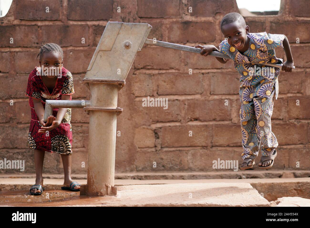 Happy Little African Boy Pumpt Wasser Für Seine Schwester Stockfoto