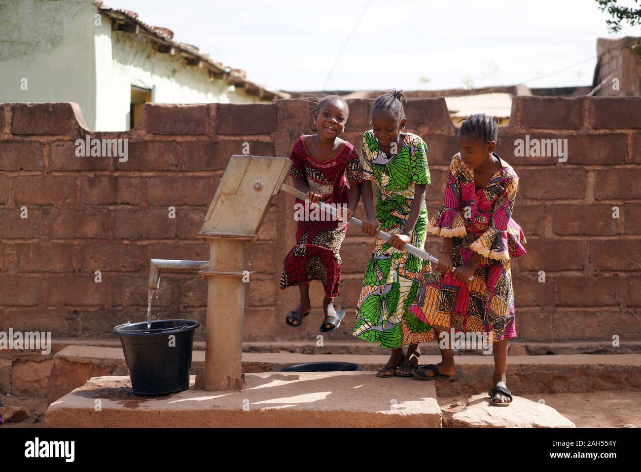 Drei Kleine Afrikanische Mädchen Haben Spaß Beim Wasserpumpen Am Bohrloch Stockfoto