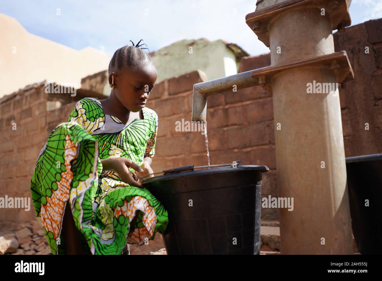 Afrikanisches Mädchen Erwägt, Die Wasserabgabe Aus Ihrem Dorfborehole Zu Bedauern Stockfoto