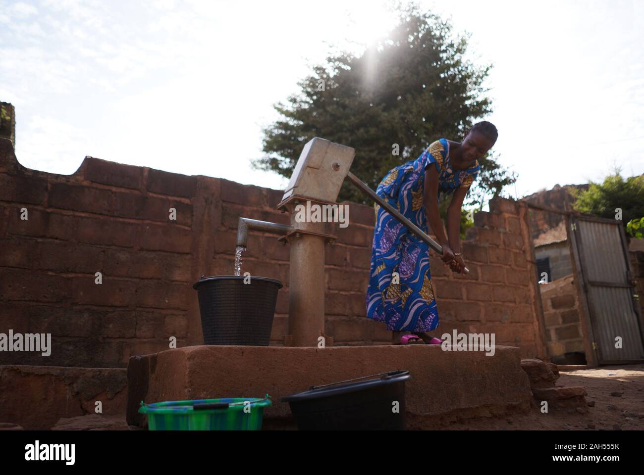 Junge Afrikanerin Füllt Eimer an der Wasserpumpe Stockfoto