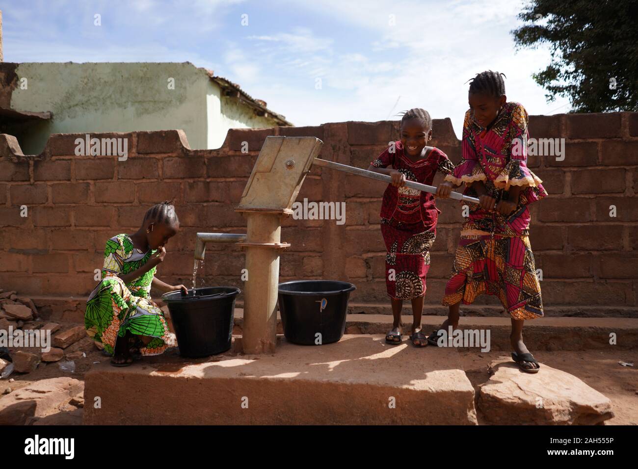 Gruppe Afrikanischer Mädchen, Die Wasser Am Bohrloch Sammeln Stockfoto