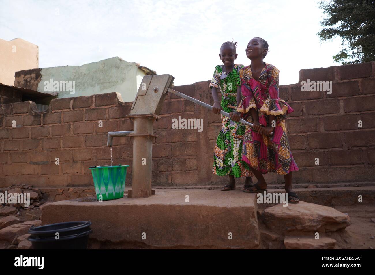 Zwei Afrikanische Mädchen Pumpen Wasser am Bohrloch Stockfoto