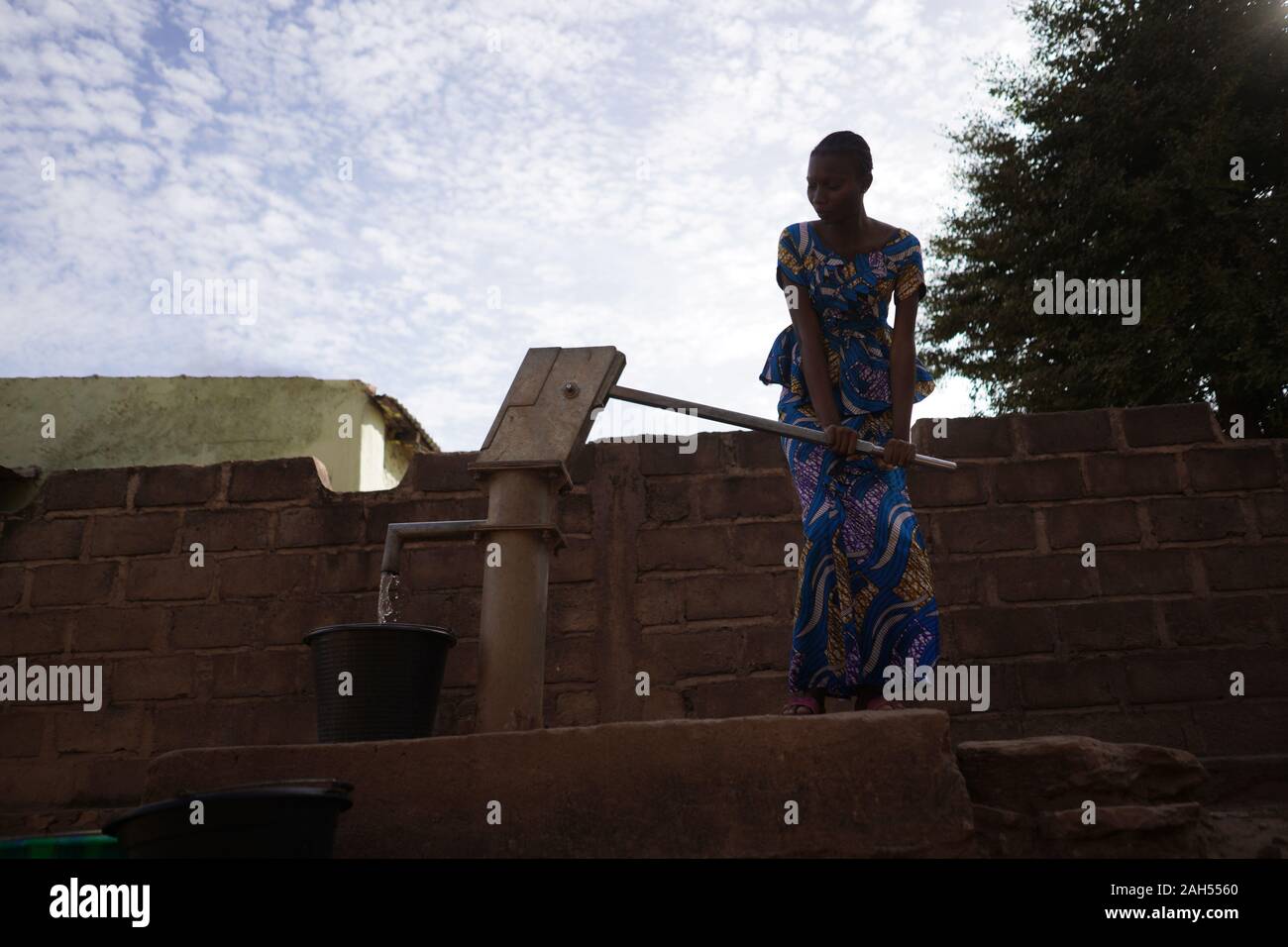African Teenage Girl Pumpt Wasser Am Bohrloch Stockfoto