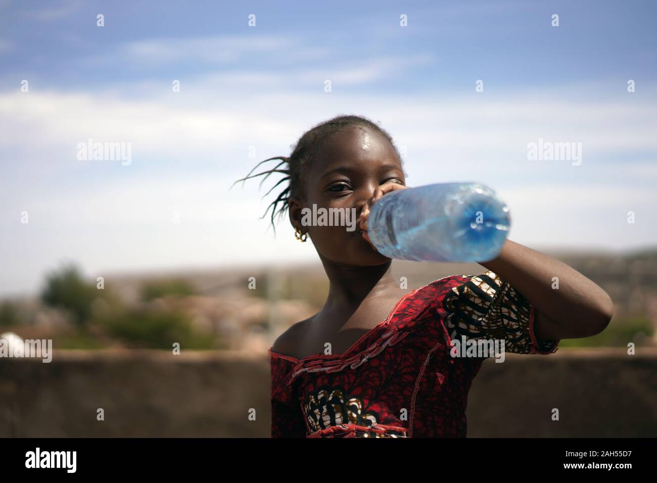 Porträt eines kleinen afrikanischen Mädchens gierig Rinking aus einer Wasserflasche Stockfoto