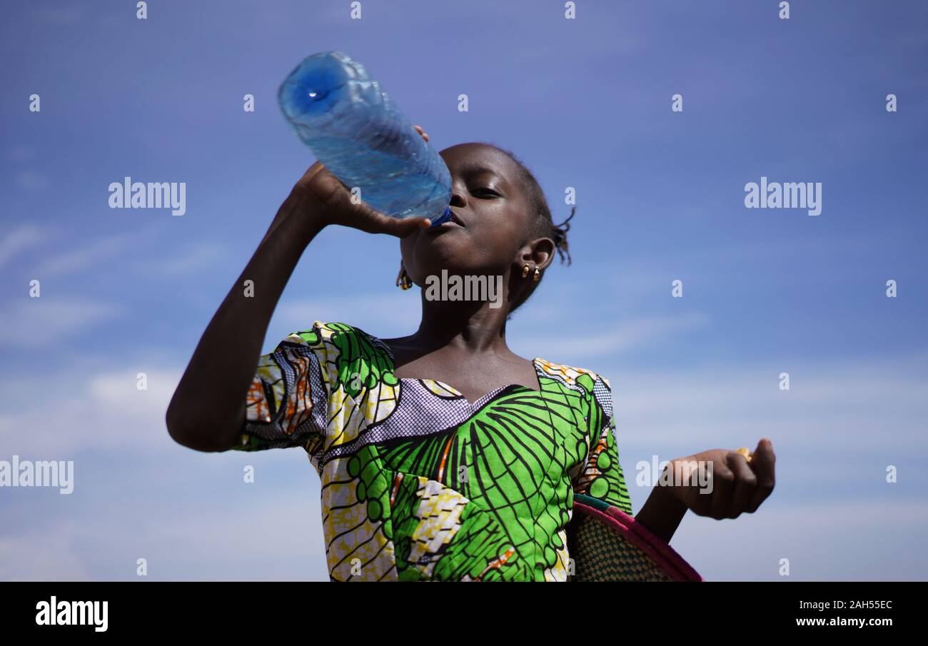 Durstig wenig afrikanisches Mädchen genießen Sie frisches Trinkwasser aus einer Kunststoffflasche Stockfoto