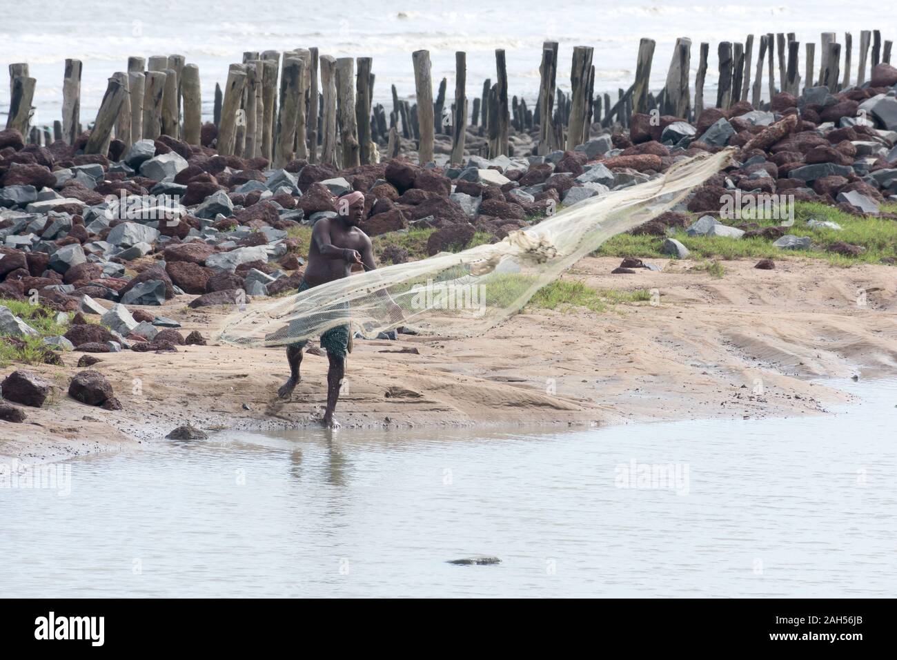 Ein Fischer werfen Fischernetz in schönen und ruhigen Achterwasser Strand in tropischen Malabarküste am Abend. Arabische Meer Küste auf Distanz. Ma Stockfoto