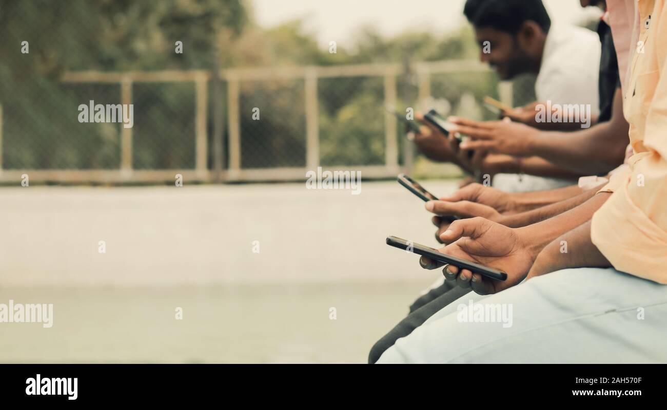 In der Nähe der Hände, junge Menschen an die Geräte süchtig - freunde gruppe sitzen in Warteschlange mit Telefone am Pool - Konzept der Millennials besetzt Stockfoto