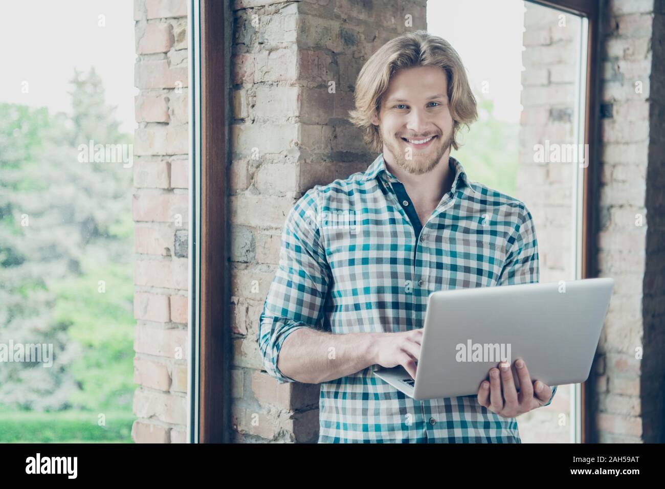 Portrait von charmanten Mann mit modernen, Technologie Lächeln tragen karierte Plaid Shirt in der industriellen Stockfoto