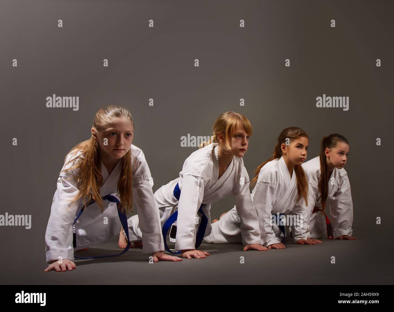 Mehrere kleine Mädchen im Karate uniformen Push up auf Ihren Händen vom Boden in der Ausbildung Stockfoto